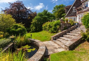 A stone staircase leading to a house with a garden and a pond.