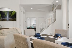 Enjoy meals in this stylish dining area with a dining table, beige chairs, and a beautiful framed photograph.