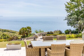 A patio with wicker furniture overlooking a coastal view. - Dorset Castle - Nine Bedroom Castle, Sleeps 20 (Easton)