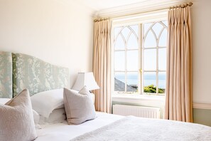 A bedroom with a bed, pillows, a lamp, and a window with curtains. - Dorset Castle - Nine Bedroom Castle, Sleeps 20 (Easton)