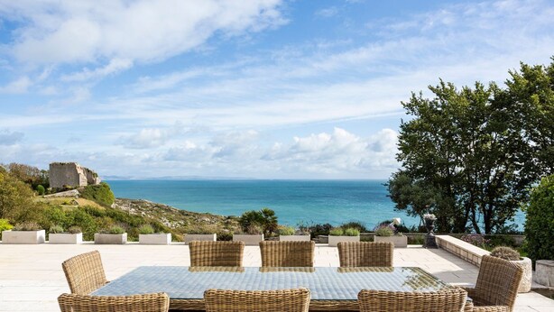 An outdoor patio with wicker furniture and a view of the sea. - Dorset Castle - Nine Bedroom Castle, Sleeps 20 (Easton)