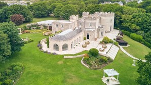 A large, historic stone building with a courtyard, surrounded by lush greenery and a well-maintained lawn. - Dorset Castle - Nine Bedroom Castle, Sleeps 20 (Easton)