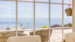 A view through a window with a stone patio, wicker furniture, and hanging plants. - Dorset Castle - Nine Bedroom Castle, Sleeps 20 (Easton)