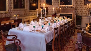 Une salle à manger élégante, avec une longue table dressée pour un repas, entourée de chaises.