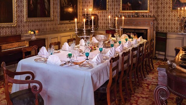 Un comedor formal con una larga mesa dispuesta para una comida, rodeada de sillas.