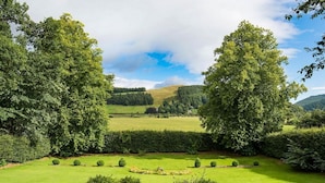 Un jardin bien entretenu, avec une variété d’arbres et d’arbustes, une pelouse soigneusement taillée et une vue dégagée sur le paysage environnant.