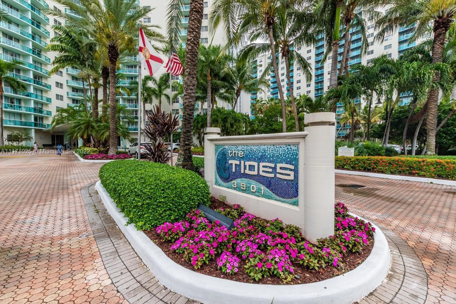 A hotel entrance with a sign reading "The Tides 3901", surrounded by palm trees and a paved walkway.