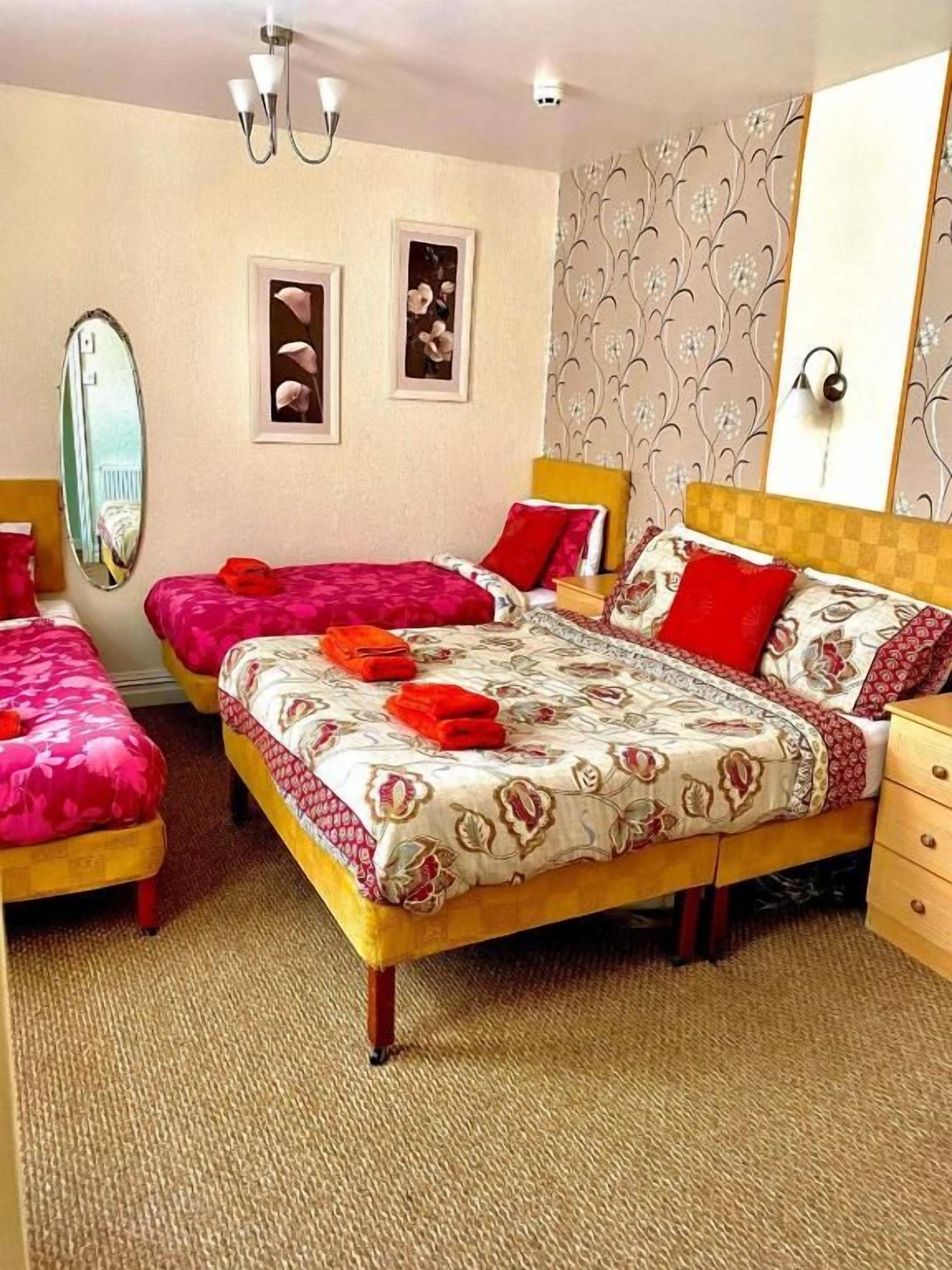 A hotel room with two beds, a mirror, and a dresser.