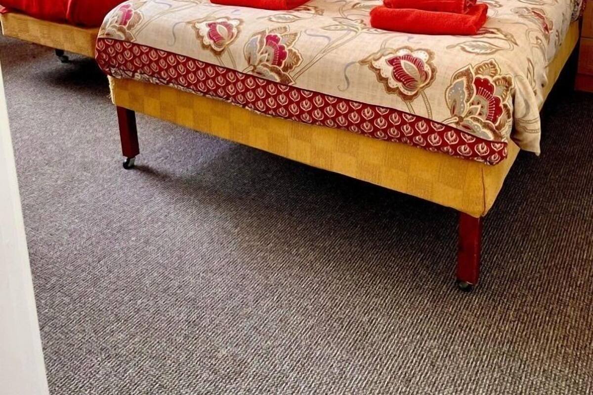 Habitación de hotel con una cama grande, dos mesitas de noche y una cortina roja.