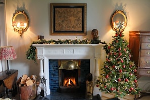 A fireplace with a Christmas tree, a mantel with decorations, and a framed artwork above.