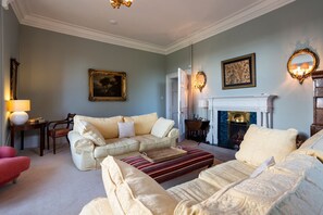 A living room with a fireplace, a sofa set, a coffee table, and a lamp. - Tarbert Country Manor (Tarbert)