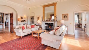 A spacious living room with a fireplace, two sofas, a coffee table, and a large mirror. - Tamar Castle - Eleven Bedroom Castle, Sleeps 22 (Landulph)