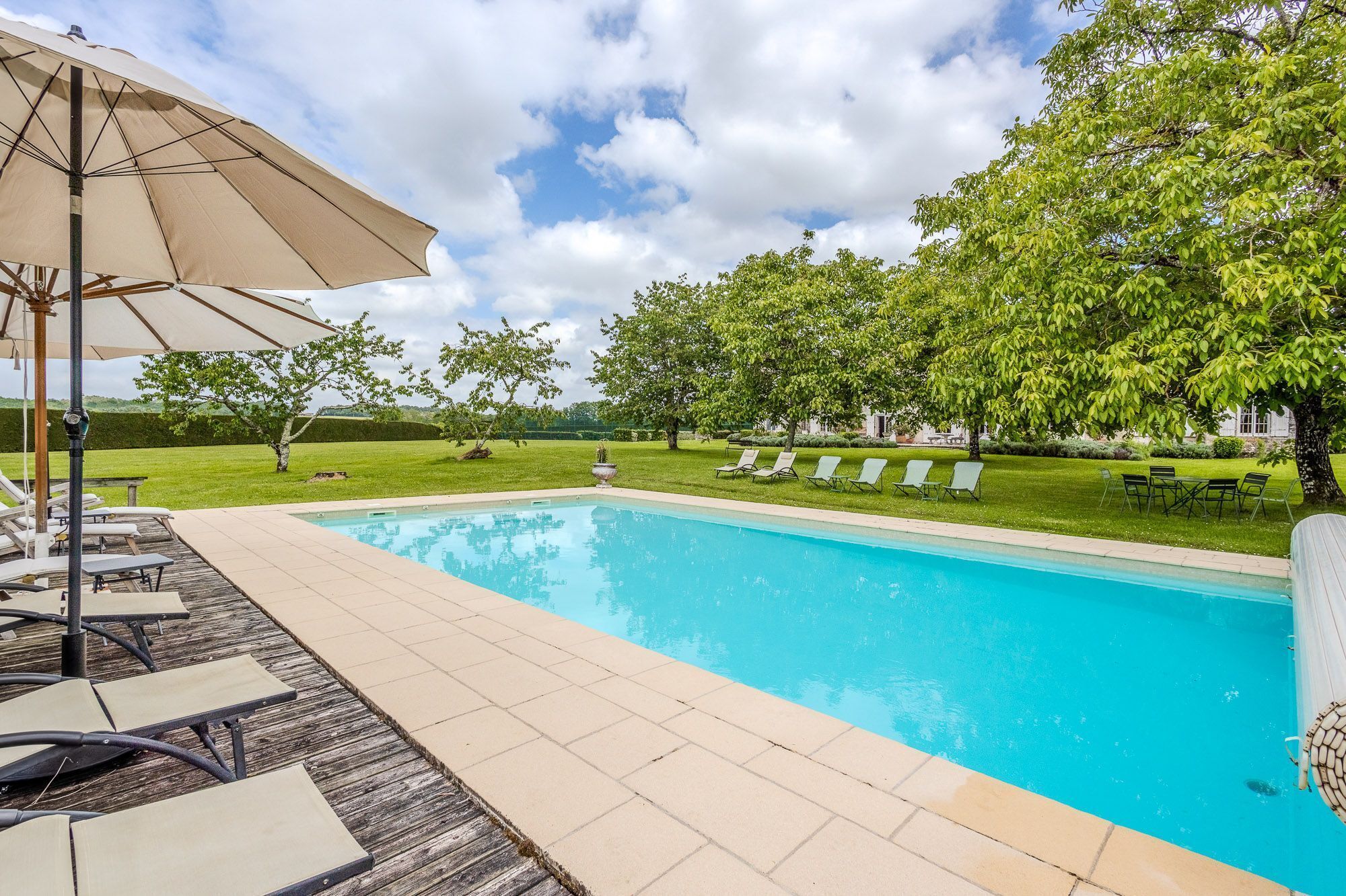 Une piscine avec des chaises longues et un parasol.