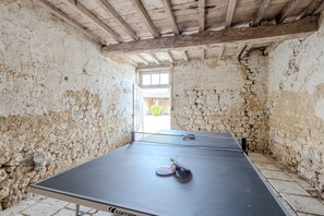 Une table de ping-pong dans une pièce aux murs en pierre et au plafond en bois.