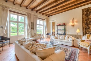 Un salon spacieux doté d’un haut plafond, de grandes fenêtres et d’un coin salon confortable avec un canapé et des fauteuils.