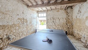 Une table de ping-pong dans une pièce aux murs en pierre et au plafond en bois.
