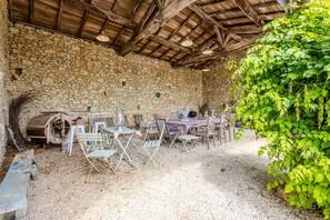 Eine Terrasse im Freien mit Steinmauern, rustikalen Holzmöbeln und verschiedenen Sitzgelegenheiten.