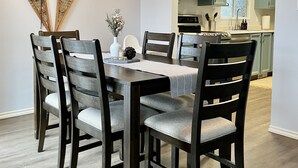 En matplats med ett mörkt träbord och stolar, en geometrisk lampa och en dekorativ väggdekoration.