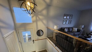En trappa leder upp till ett vardagsrum med en soffa, en lampa och inramade tavlor på väggen.