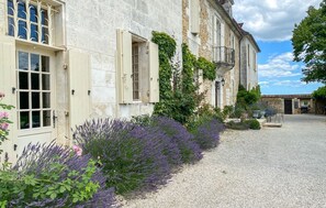 A historic stone building with a gravel courtyard, a row of lavender, and a small outdoor seating area. - Chateau De Neveu - Seven Bedroom Castle, Sleeps 14 (Saint-Martin-des-Combes)