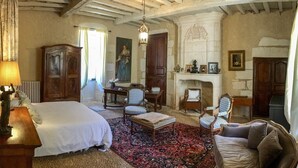Una habitación tradicional con una cama, dos sillones, un sofá, una chimenea y un tapiz grande.