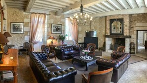 Un salón tradicional con chimenea, sofás de cuero y una araña.