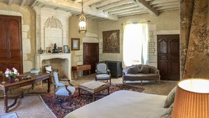 Una habitación tradicional con chimenea, cama, escritorio y sillón.