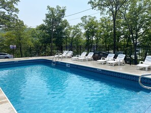 Relax by the serene pool surrounded by lush greenery and lounge chairs.