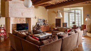 Una sala rústica con un sofá grande, vigas de madera, un televisor y una chimenea.