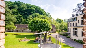 Une cour avec un trampoline, un espace salon abrité et des bâtiments en pierre en arrière-plan.