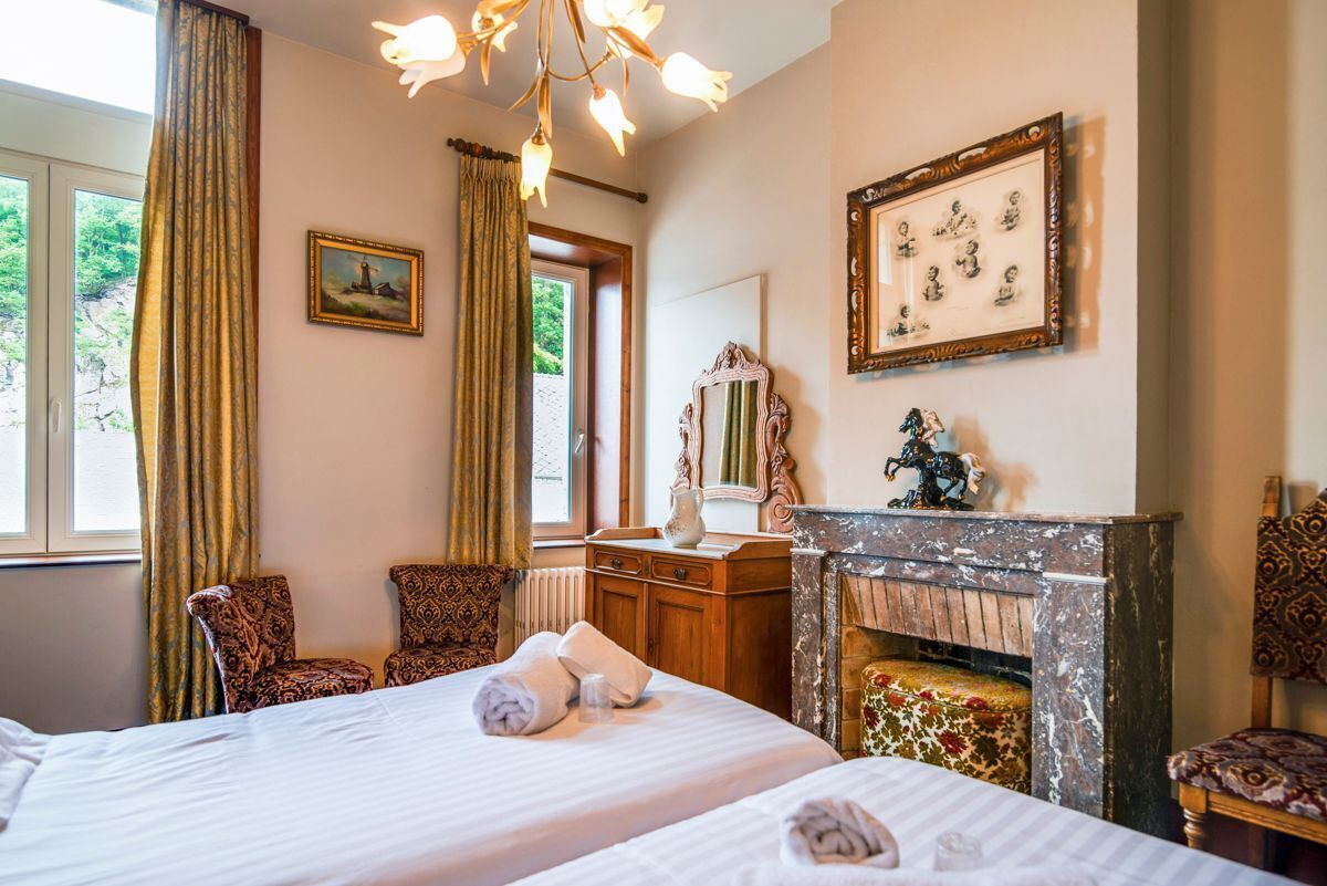 Quarto de hotel com duas camas, lareira, espelho e janela com cortinas.