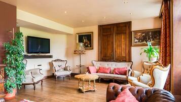 A traditional living room with a sofa, armchairs, a coffee table, and a television.