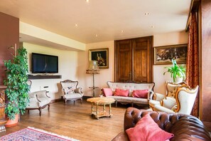 Uma sala de estar tradicional com sofá, poltronas, mesa de centro e televisão.
