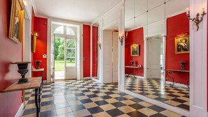 Un couloir doté d’un sol à carreaux, de murs rouges et d’un miroir qui reflète la pièce.
