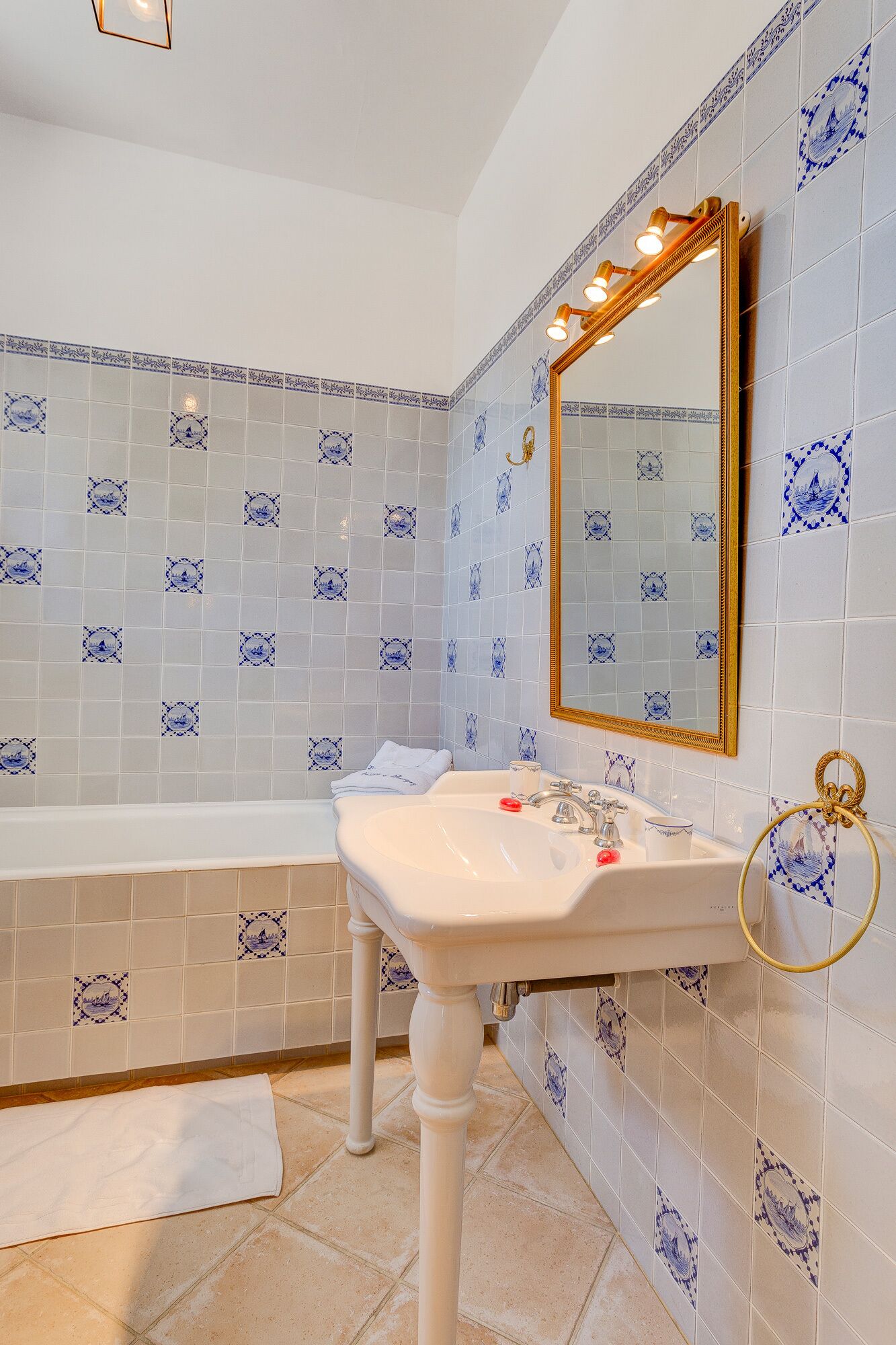 Een badkamer met een wit wastafel, een badkuip en een spiegel met gouden lijst.
