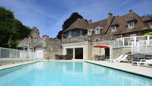A swimming pool with lounge chairs and a wooden deck.