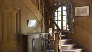 A wooden staircase with a handrail, a chair, and a cabinet.