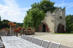 Un espace de restauration extérieur de style rustique, avec un bâtiment en pierre, des tables et des chaises en bois.