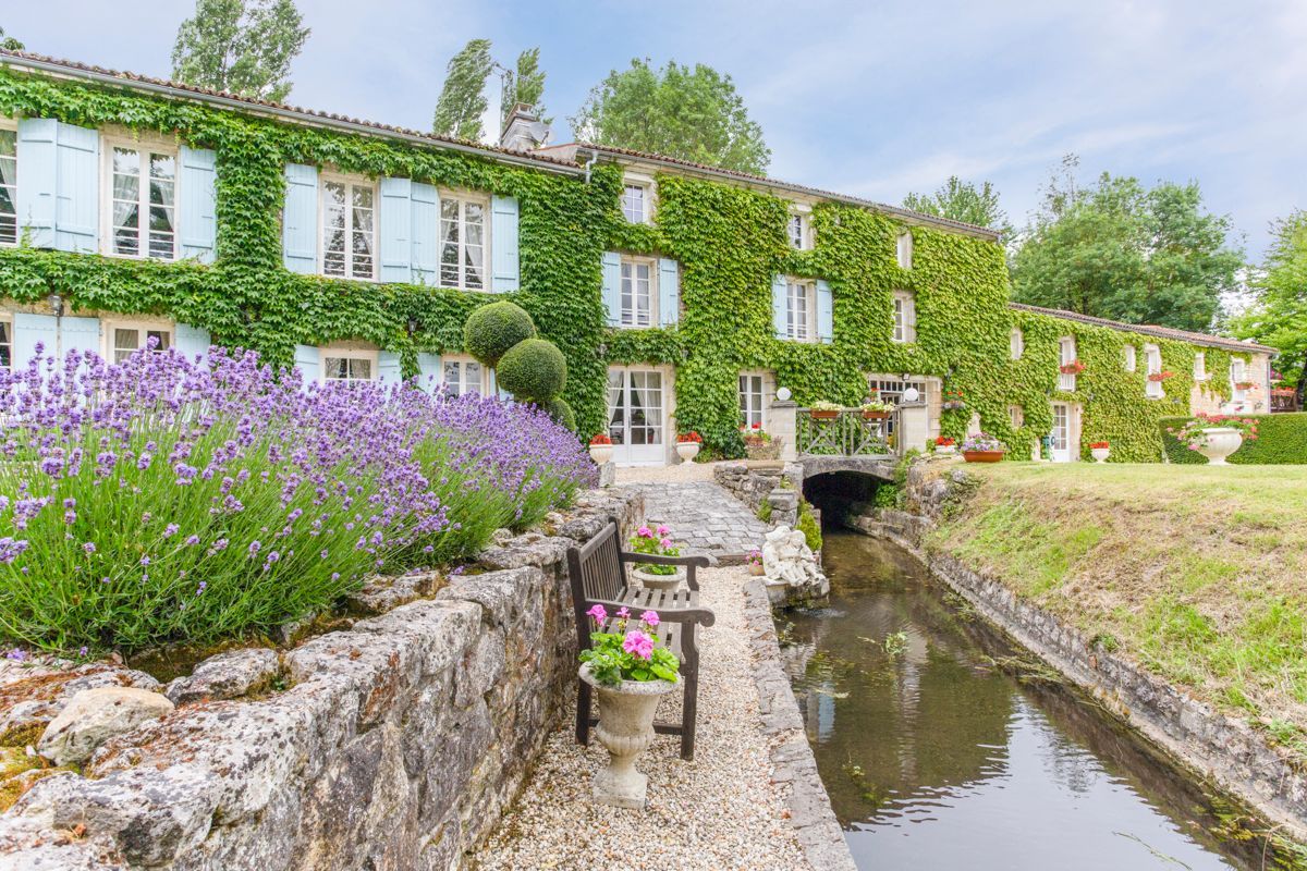 A building with ivy-covered walls, a canal, and a bridge.