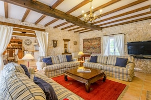 Una sala acogedora con sofás a rayas, una mesa de centro de madera y una pared de piedra.