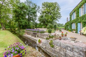 A garden with a narrow water channel, stone walls, and various potted plants.
