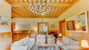 Un amplio salón con techo de madera, sofás blancos, una mesa de centro y una araña.
