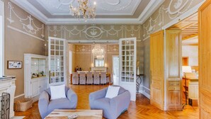 Un salón amplio con piso de madera, dos sofás grises, una mesa de centro y un candelabro.