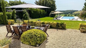 Een terras met een tafel, stoelen en een grote parasol.