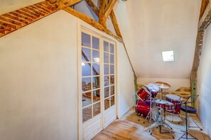 Um quarto com teto inclinado, uma janela grande e um set de bateria.