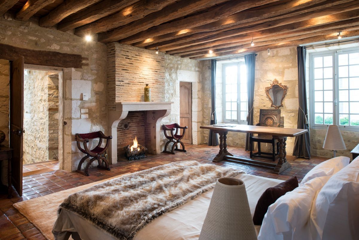 Une pièce rustique aux murs de pierre, dotée d’une cheminée, de meubles en bois et d’un grand tapis en fourrure.