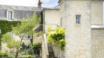 Un bâtiment en pierre avec une piscine et des chaises longues.