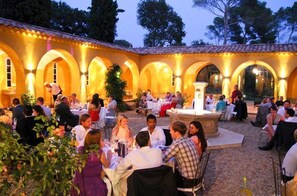 An outdoor dining area with arches and a fountain, surrounded by guests.