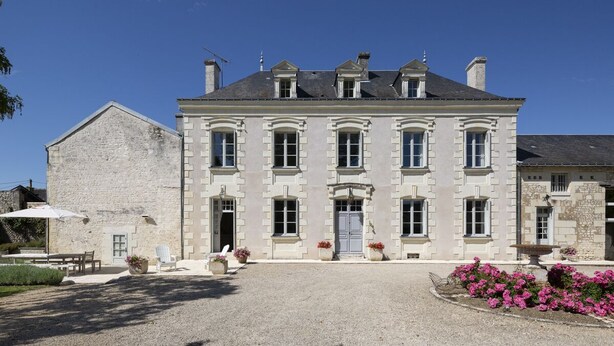 Un grand bâtiment historique en pierre, doté d’une façade symétrique, de nombreuses fenêtres et d’une entrée centrale.