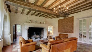 A spacious living room with a fireplace, leather sofas, and a tiled floor. - Chateau Roussignol - Twelve Bedroom Castle, Sleeps 28 (Le Blanc)